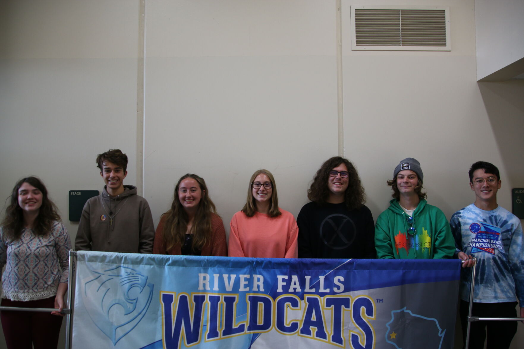 Marching band students posing with banner.JPG